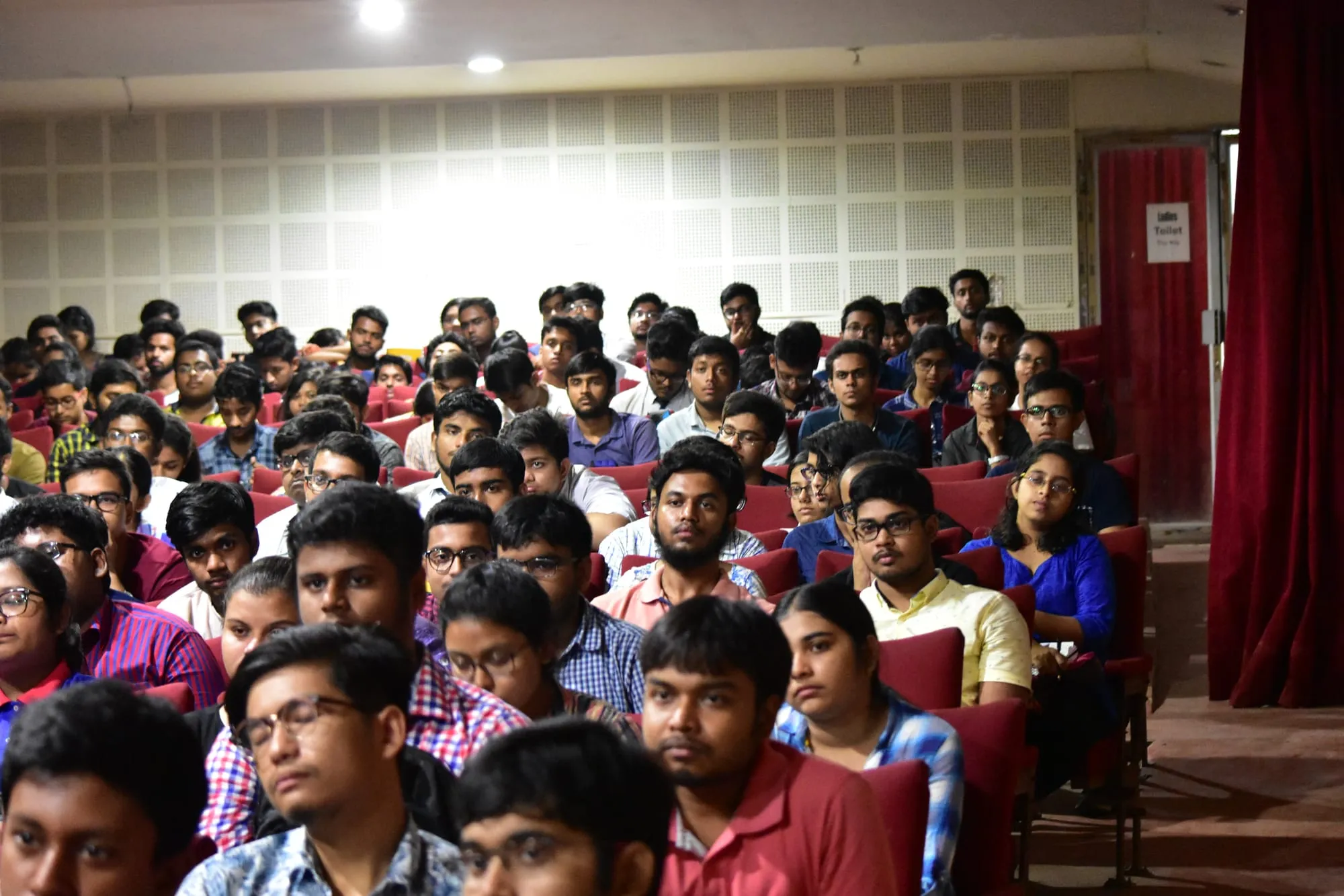 A packed auditorium of students facing the stage during a workshop.