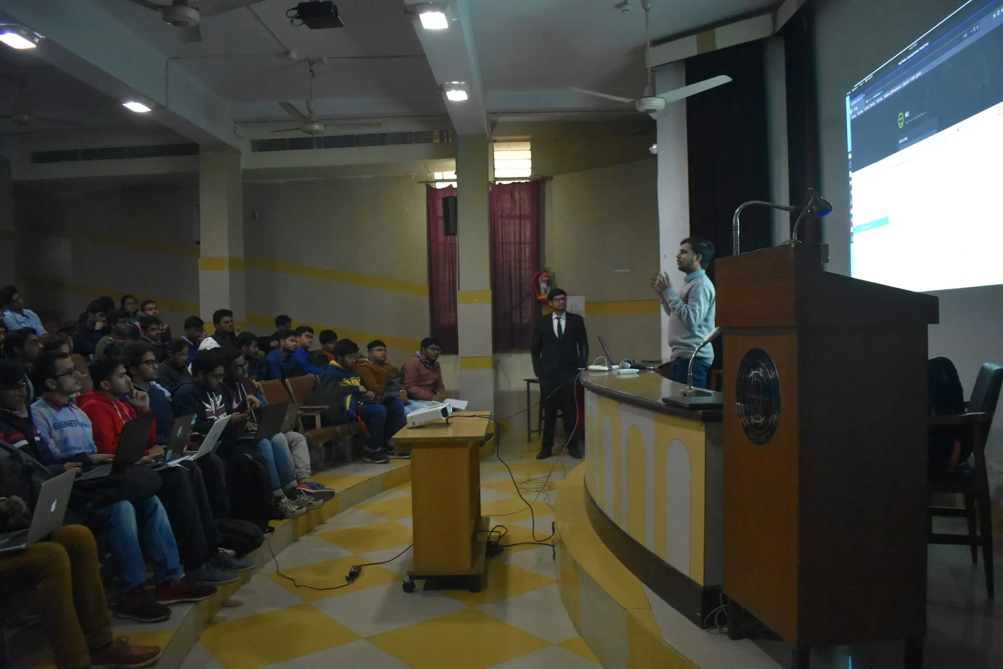 The hall during a session, seen from the back, with the screen lit at the front.