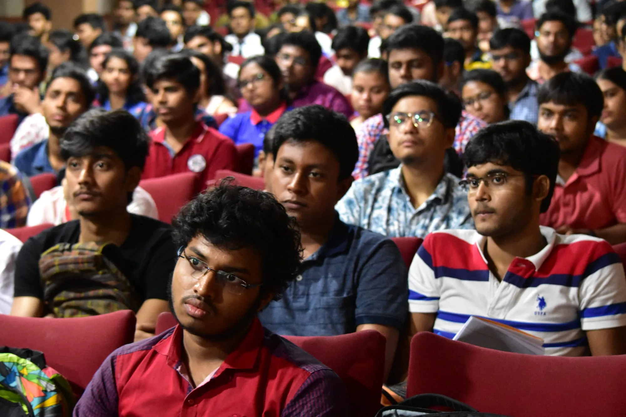 Rows of students listening closely from the front of the auditorium.